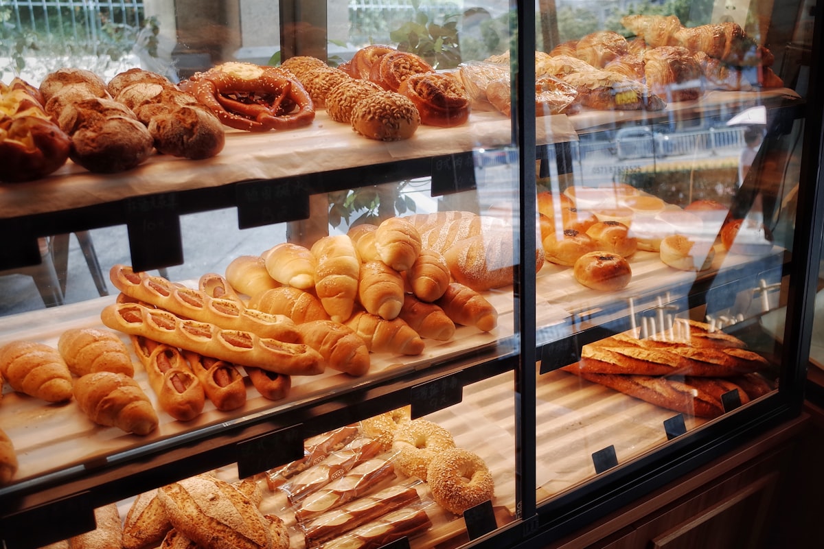 Rijen ambachtelijke broden op houten planken in Bakkerij De Desemhoek
