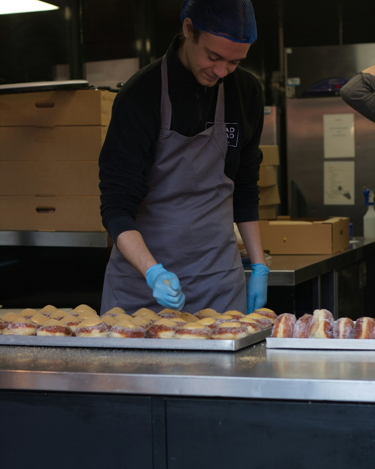 Bakker bereidt brood voor in de keuken van Bakkerij De Desemhoek, schort aan, warm licht